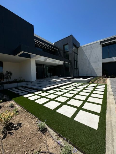 Modern house exterior with square concrete pavers set in artificial turf.