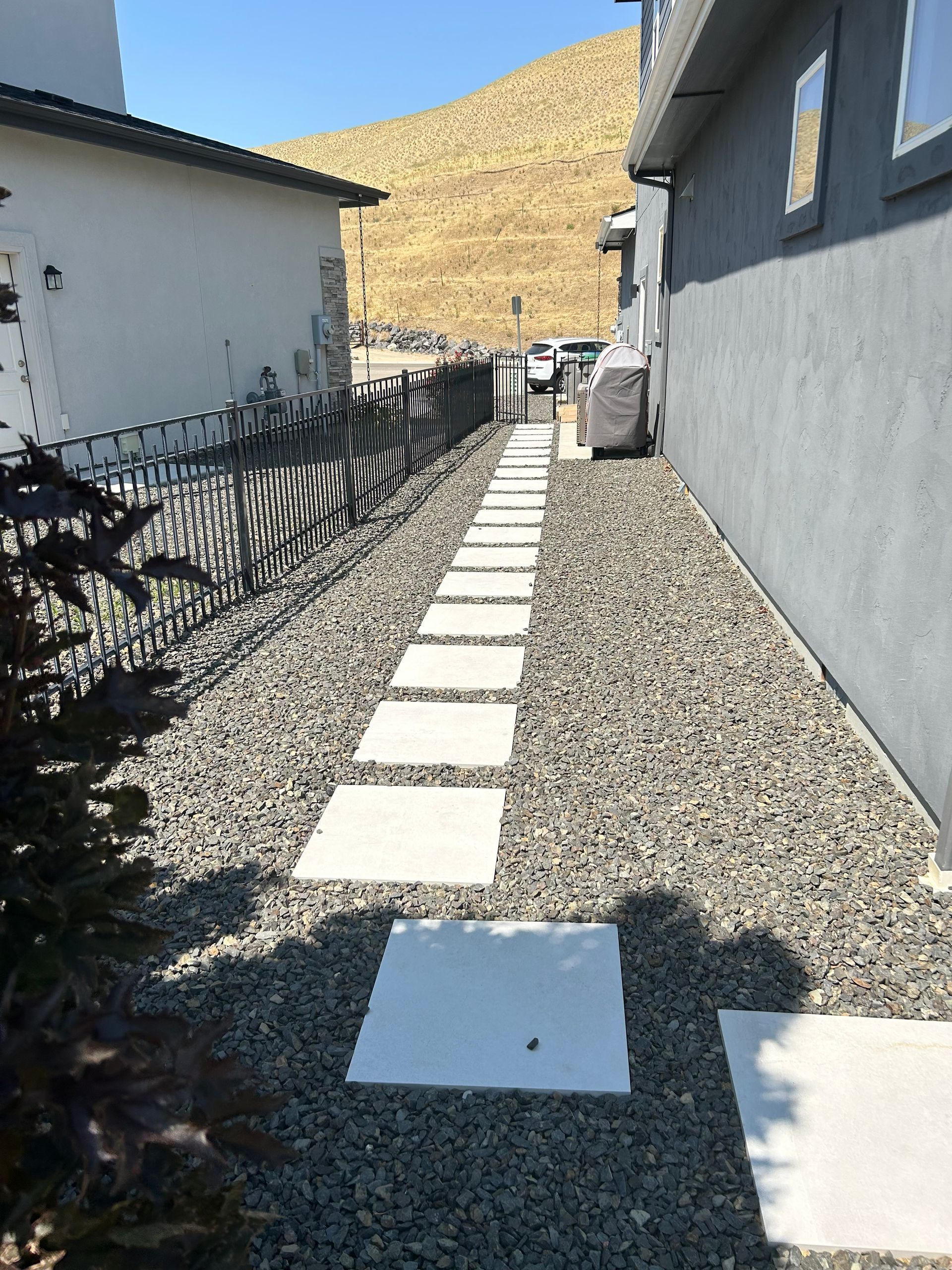 Pathway with concrete stepping stones and gravel between buildings.