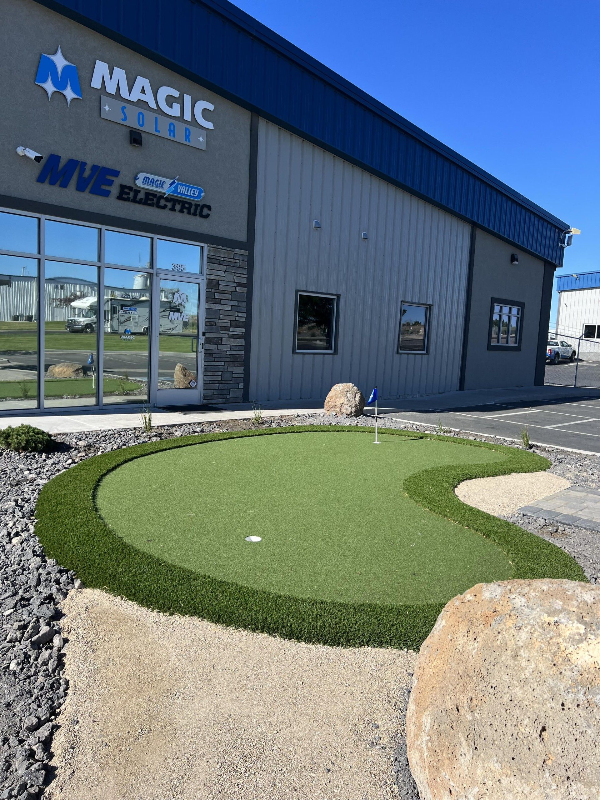 Exterior of a building with a putting green in front. 
