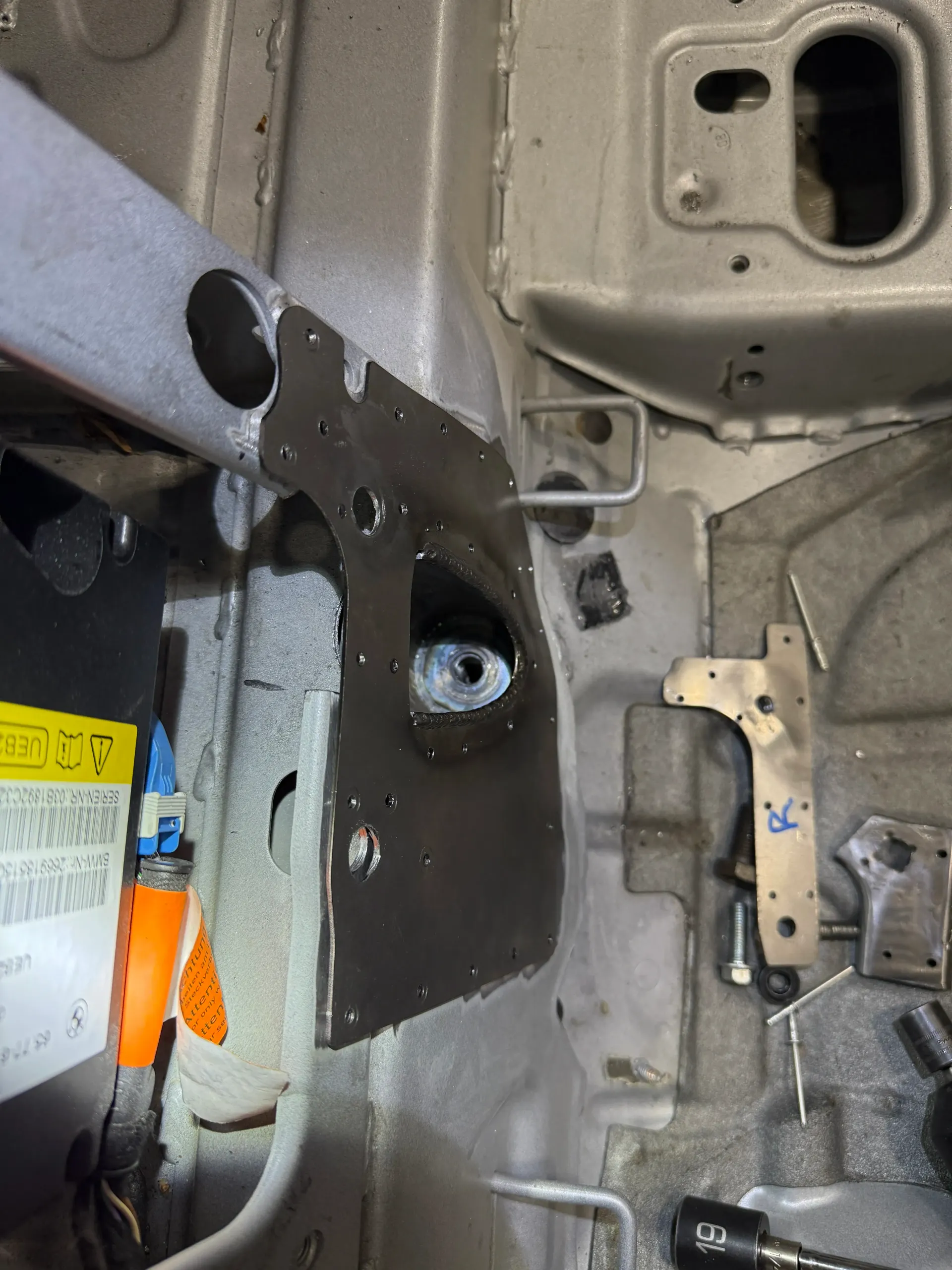 Metal car frame with a large hole, a welded brace, and various mounting brackets. | GermanTech MotorWorks, LLC