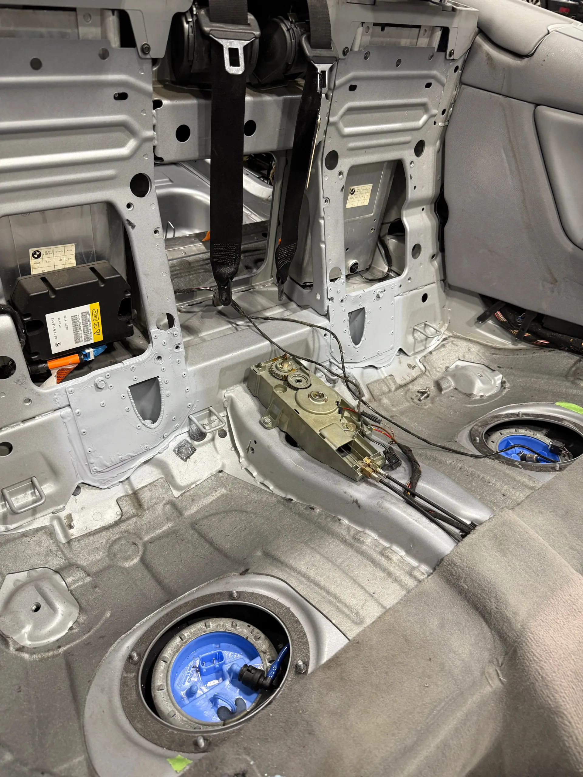 Car's interior with the seats and carpet removed, revealing the metal frame, fuel tanks, and wiring. | GermanTech MotorWorks, LLC
