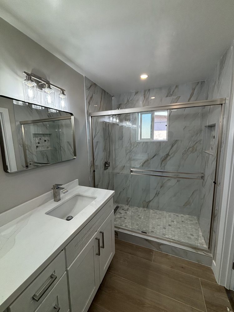 A bathroom with a sink , mirror and shower.