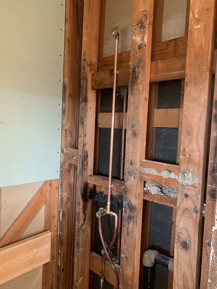 A wooden wall with a copper pipe hanging from it.