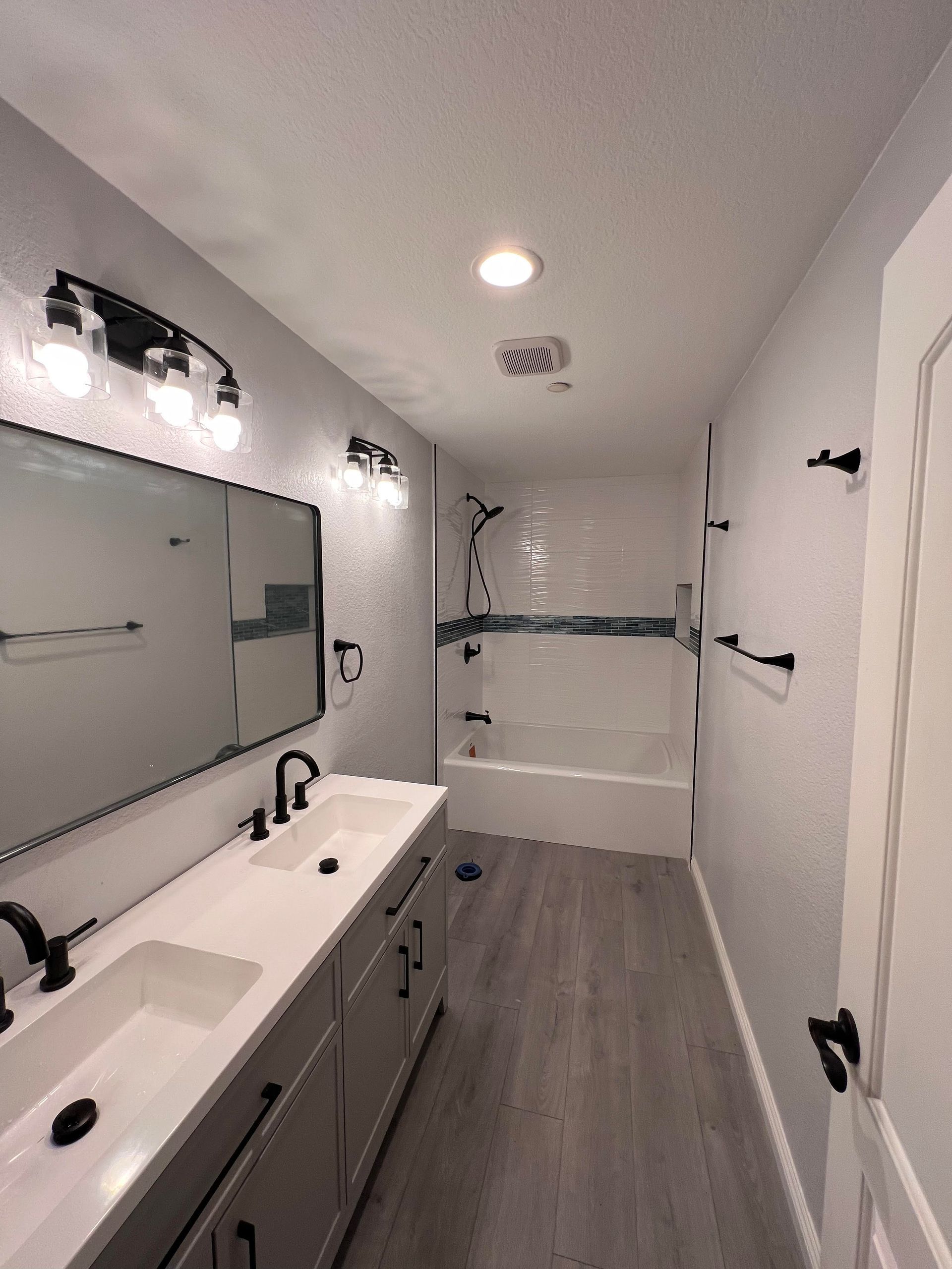 A bathroom with two sinks , a tub and a mirror.