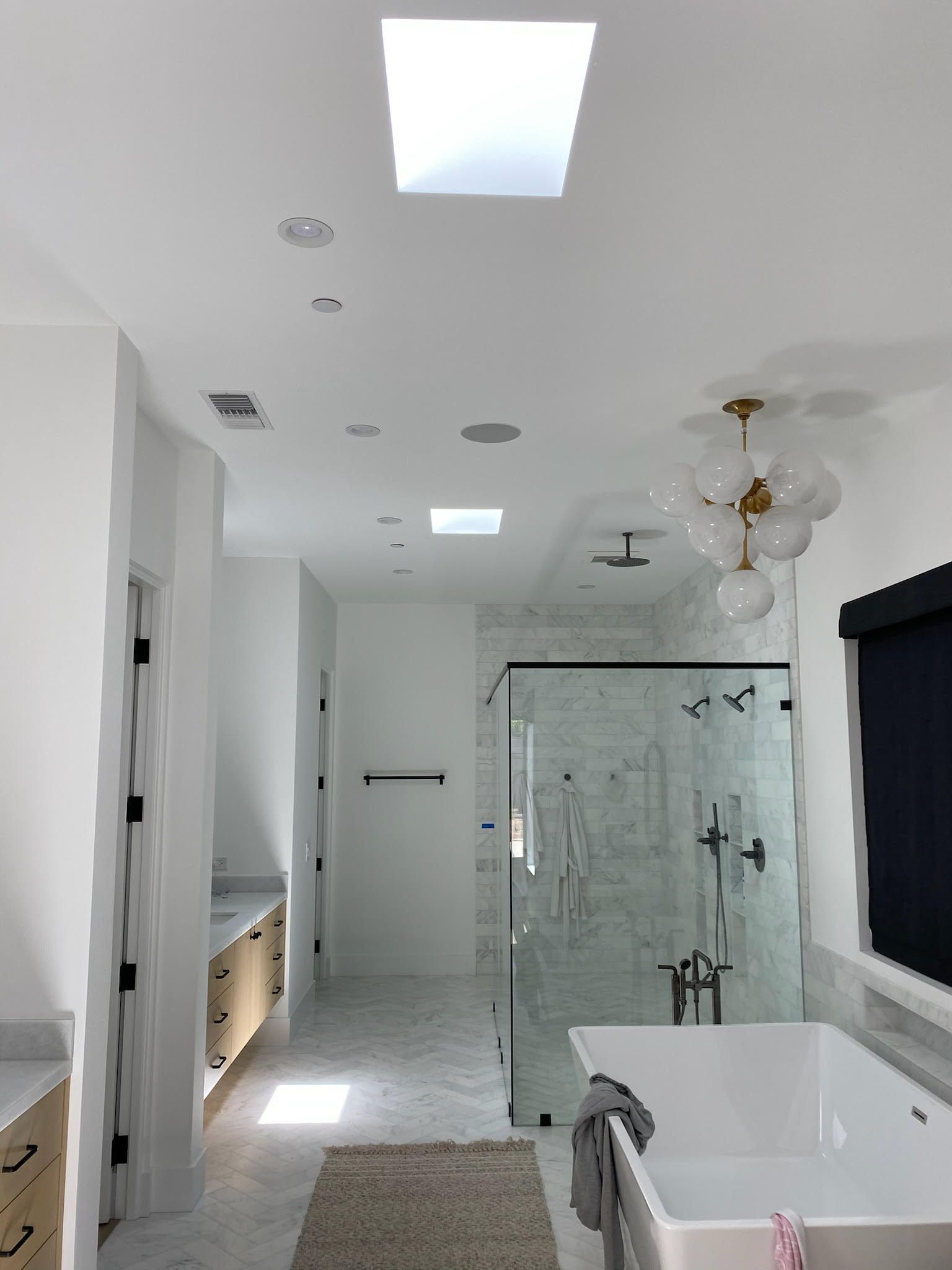 A bathroom with a tub , shower , and skylight.