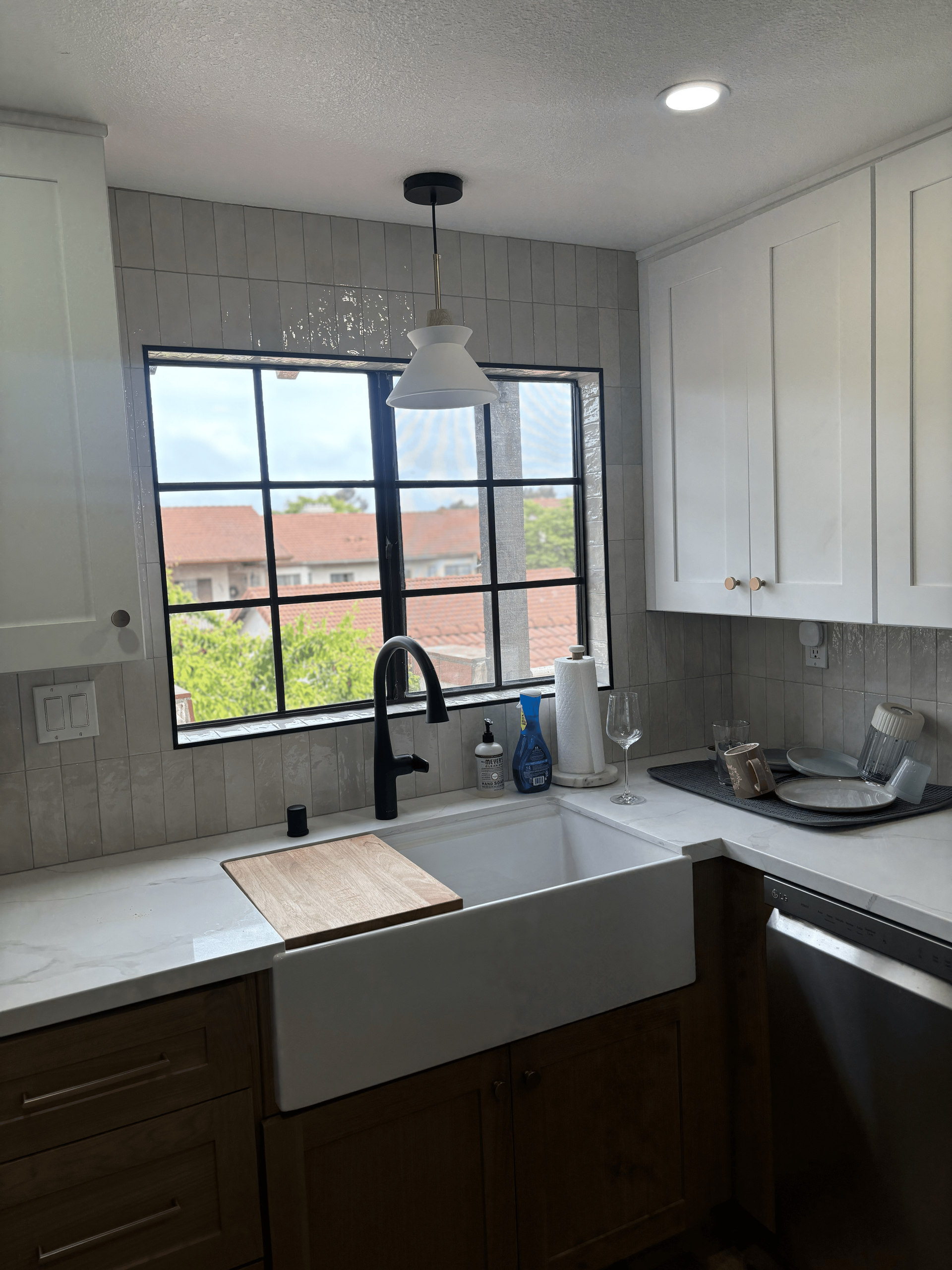 A kitchen with a sink , cabinets , and a window.