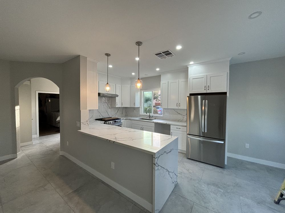 A kitchen with white cabinets , stainless steel appliances , and a large island.