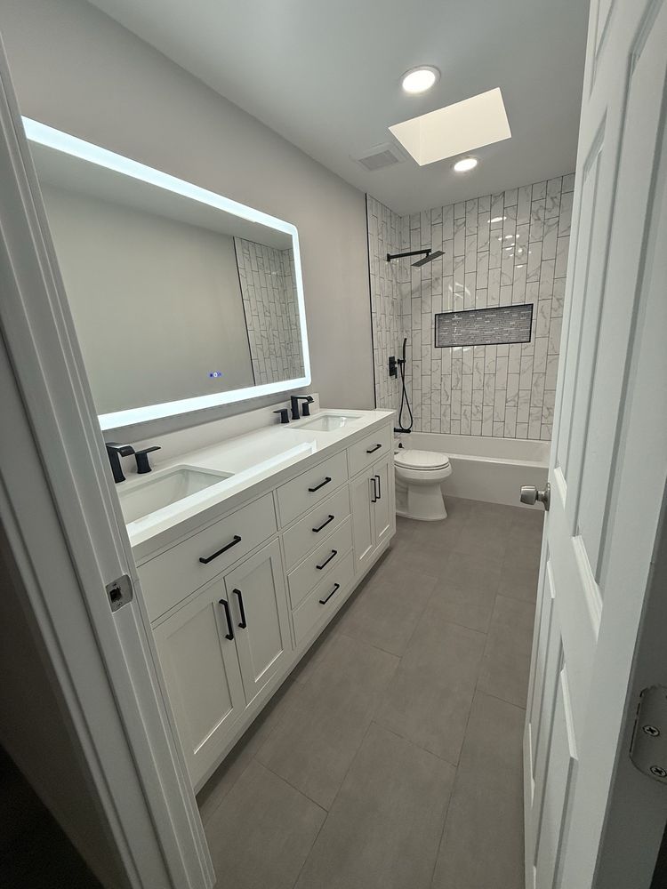 A bathroom with a toilet , sink , mirror and tub.