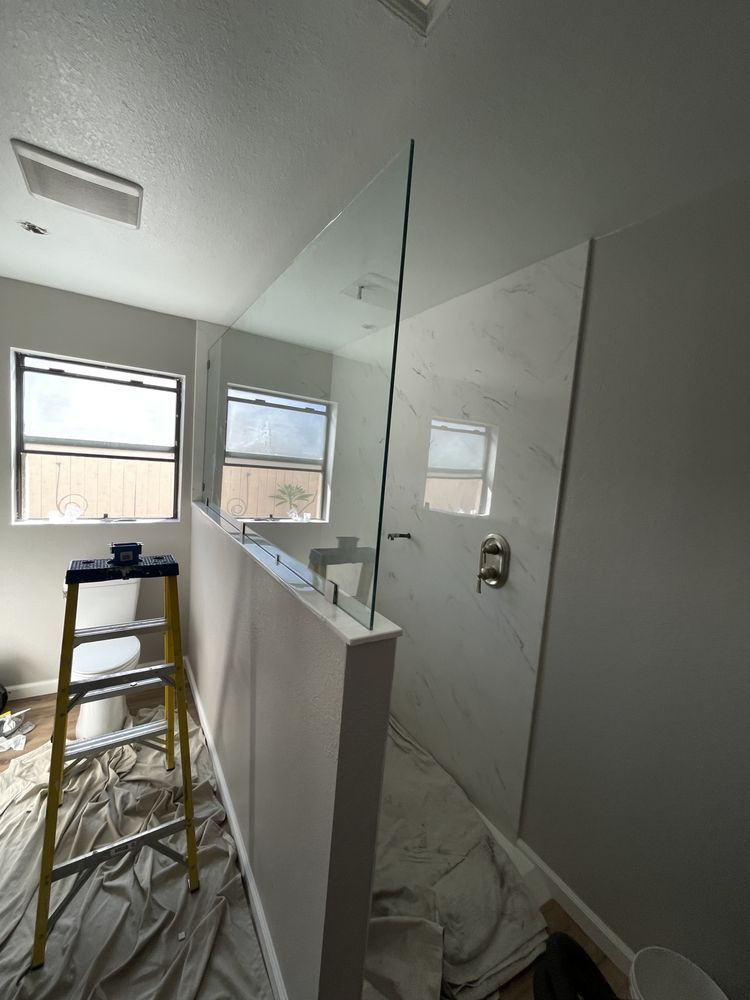 A bathroom with a ladder and a glass shower door