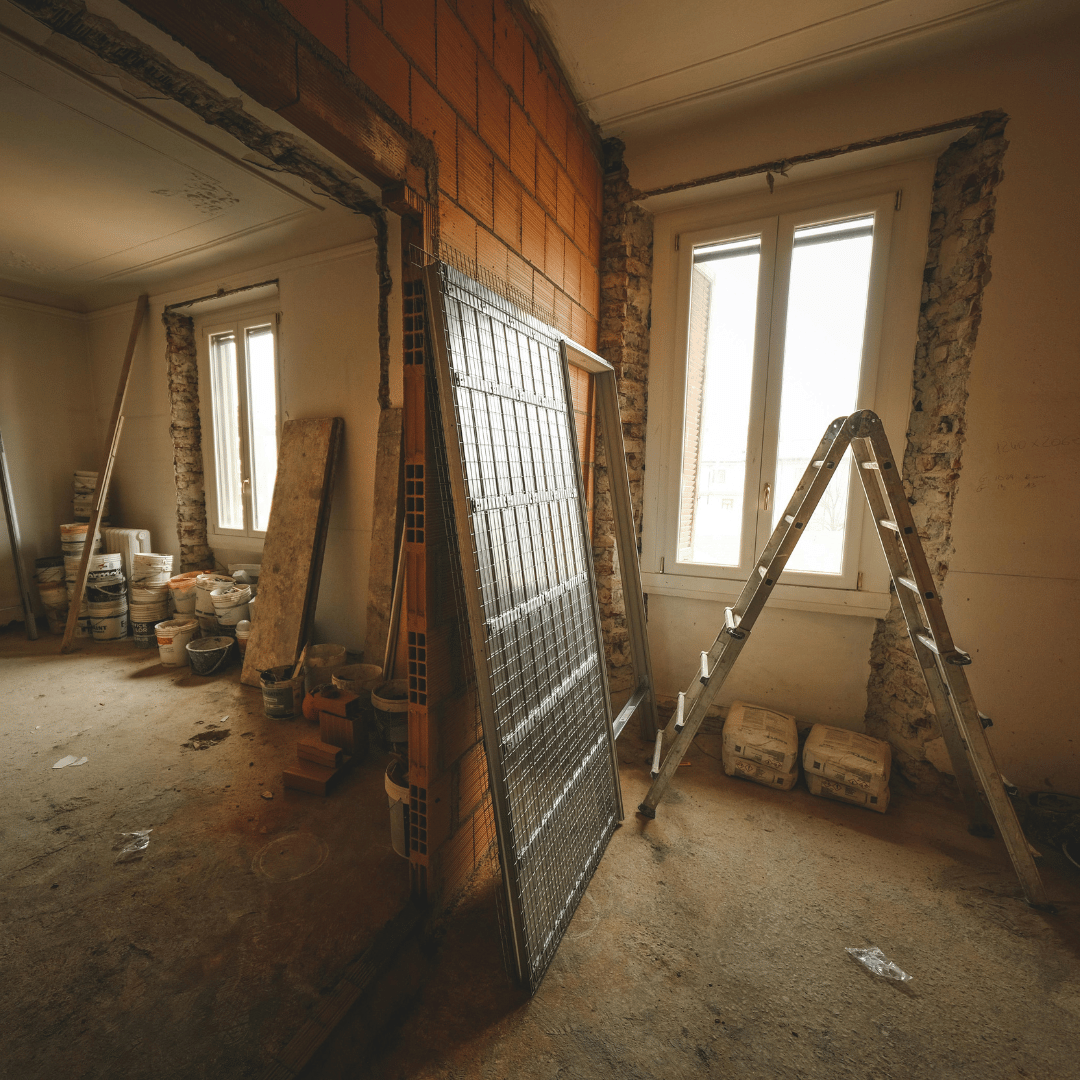 An empty room with a ladder and a brick wall