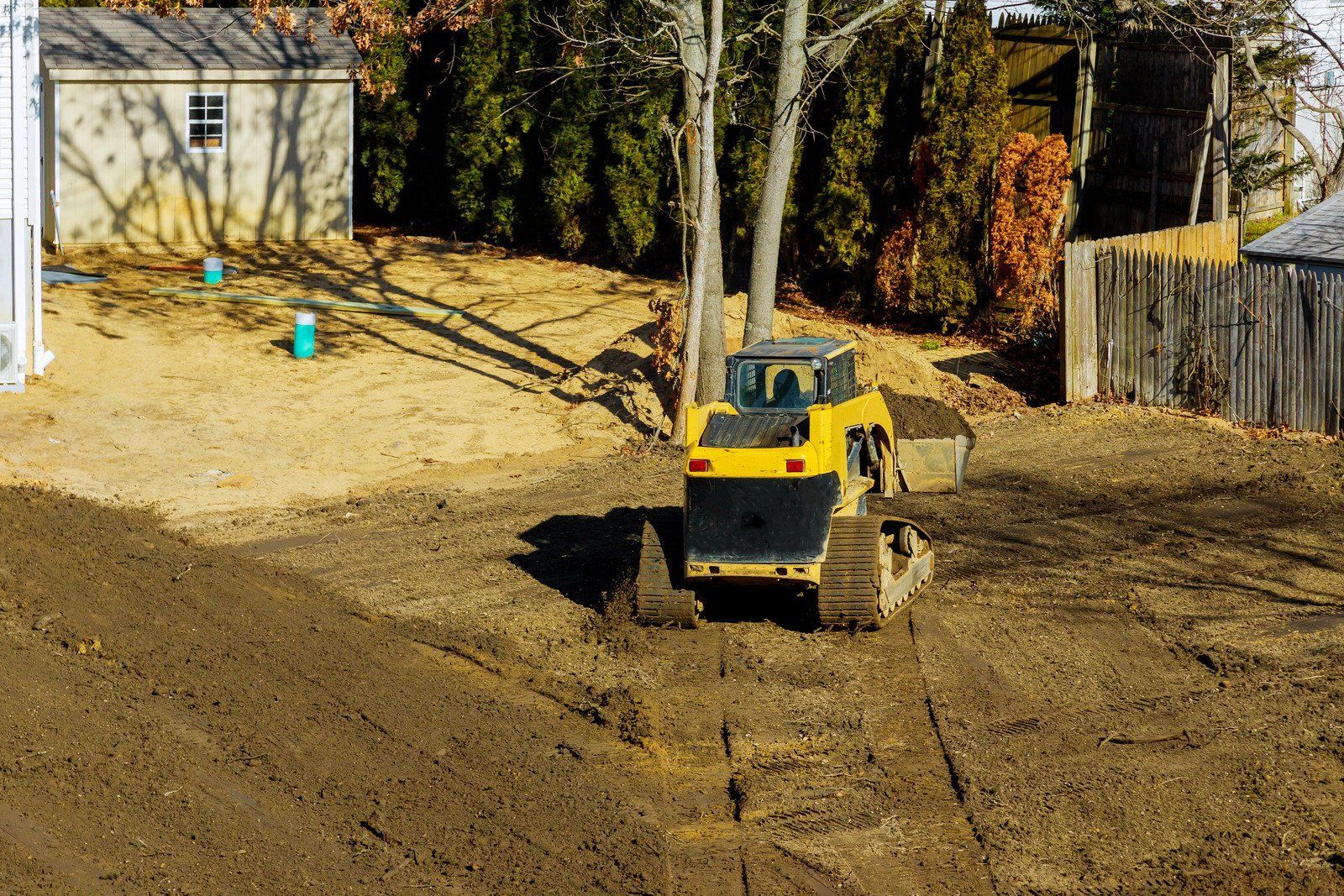 A yellow excavator is sitting on top of a pile of gravel.