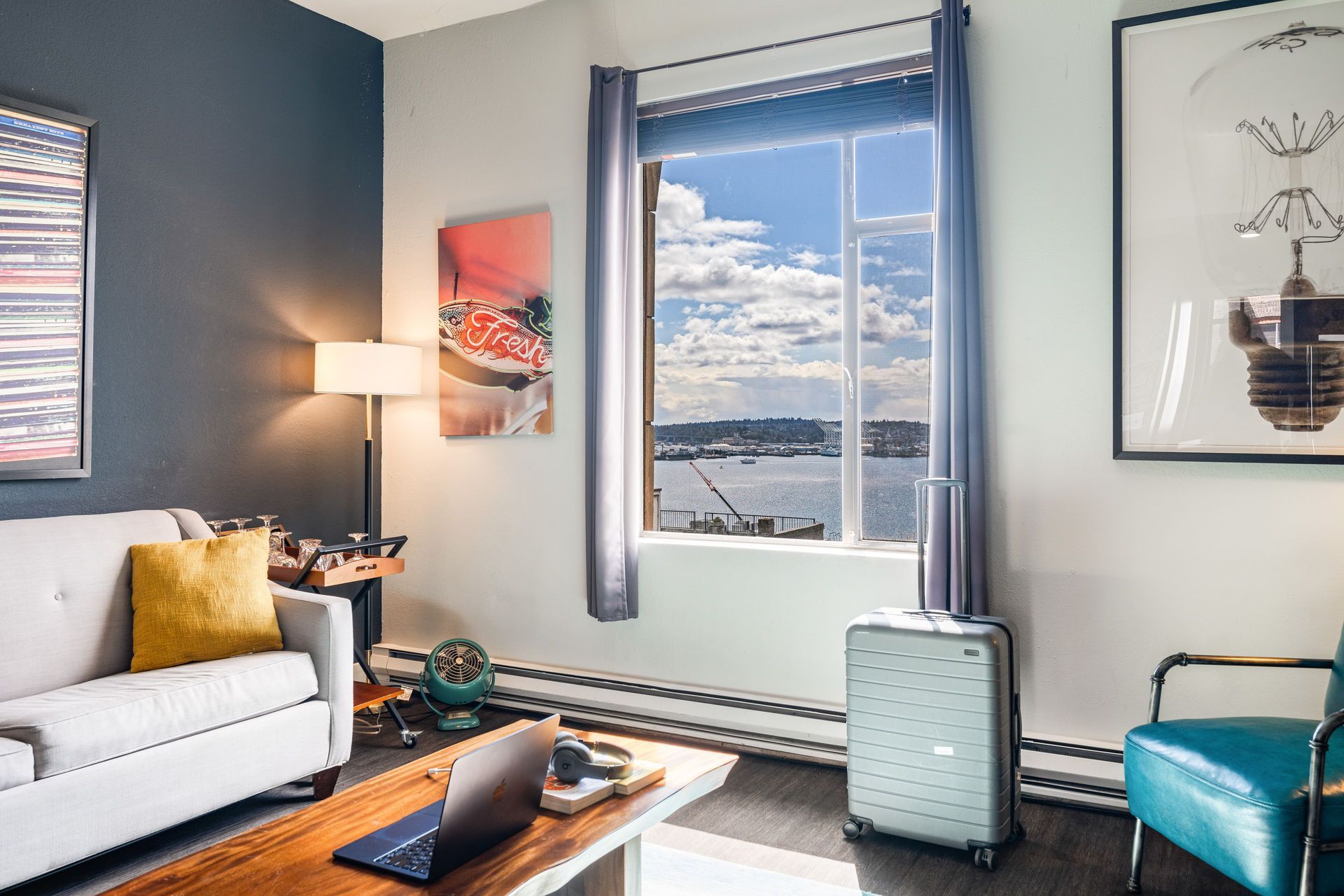 Cozy room with a white couch, wooden table, and a suitcase. Large window with a scenic view.