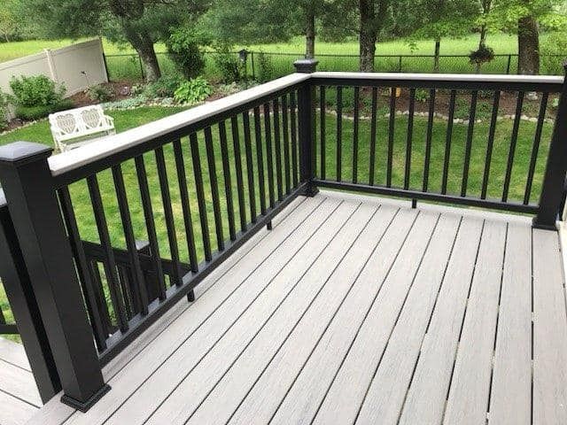 A deck with a black railing and a bench in the background.