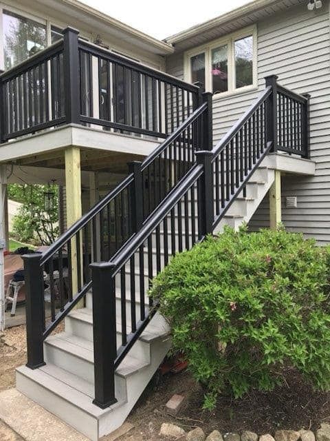 A deck with stairs leading up to it and a black railing