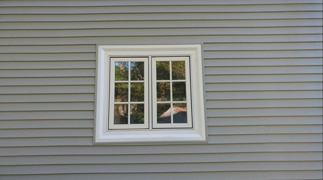A white window is on the side of a house.