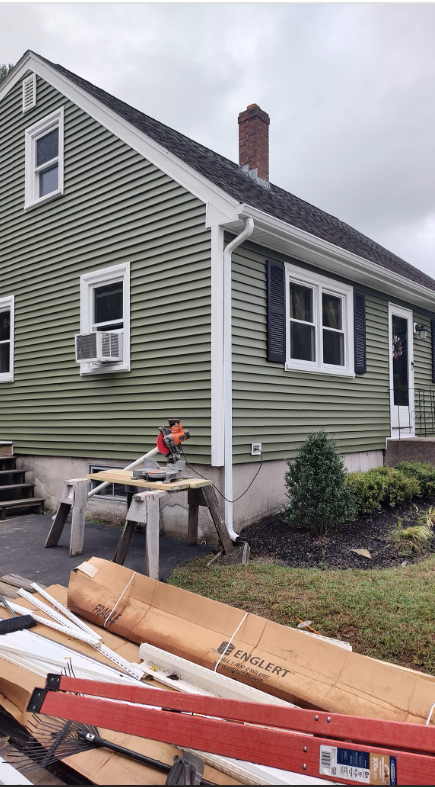 A green house with a ladder in front of it.