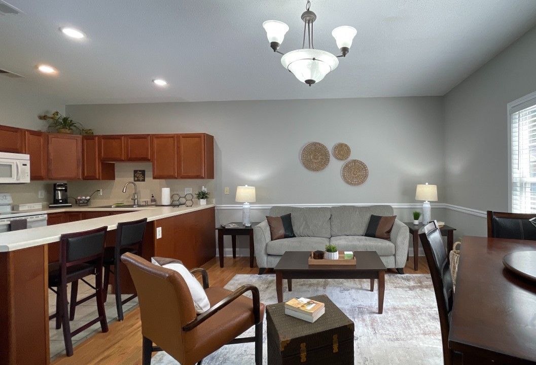 A living room with a couch , chair , coffee table and kitchen.