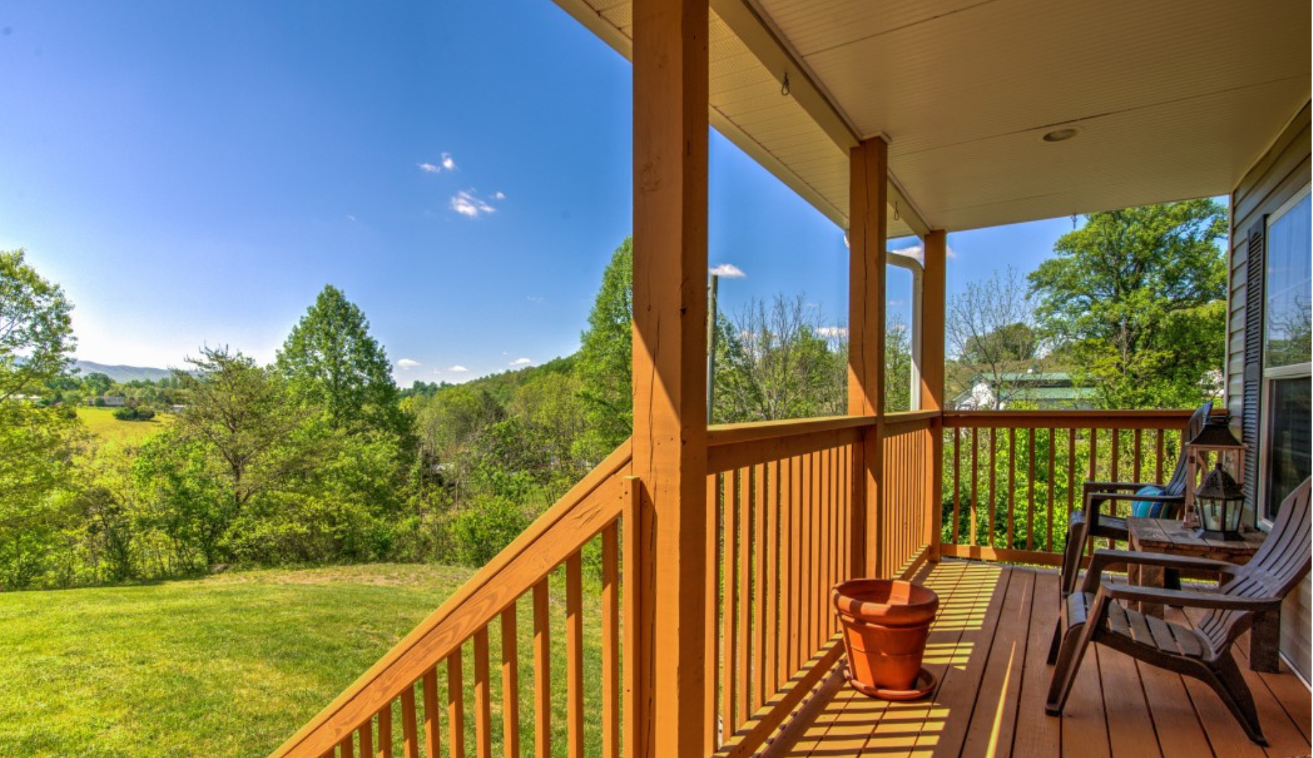 A wooden deck with chairs and a potted plant on it