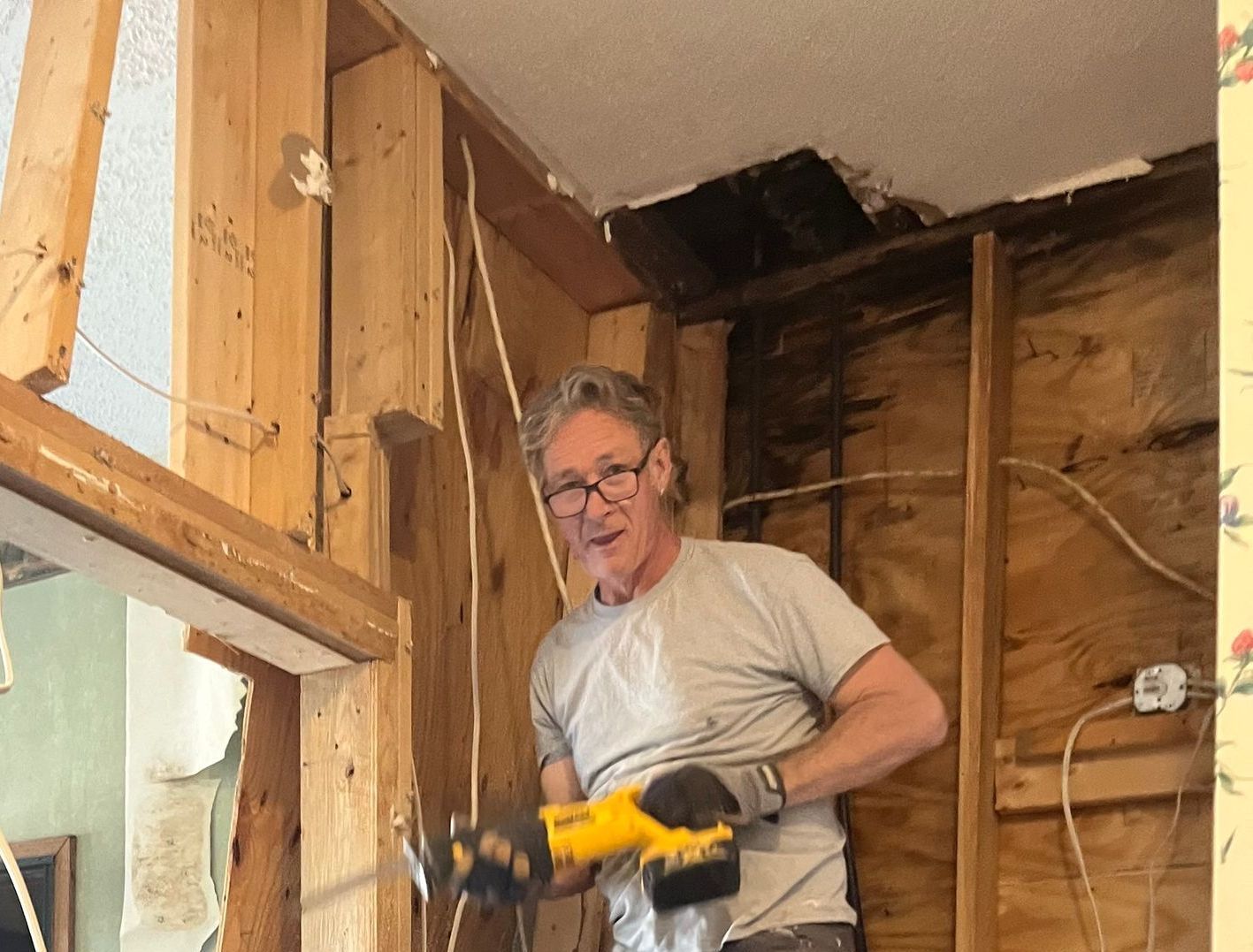 A man is working on a wall with a drill