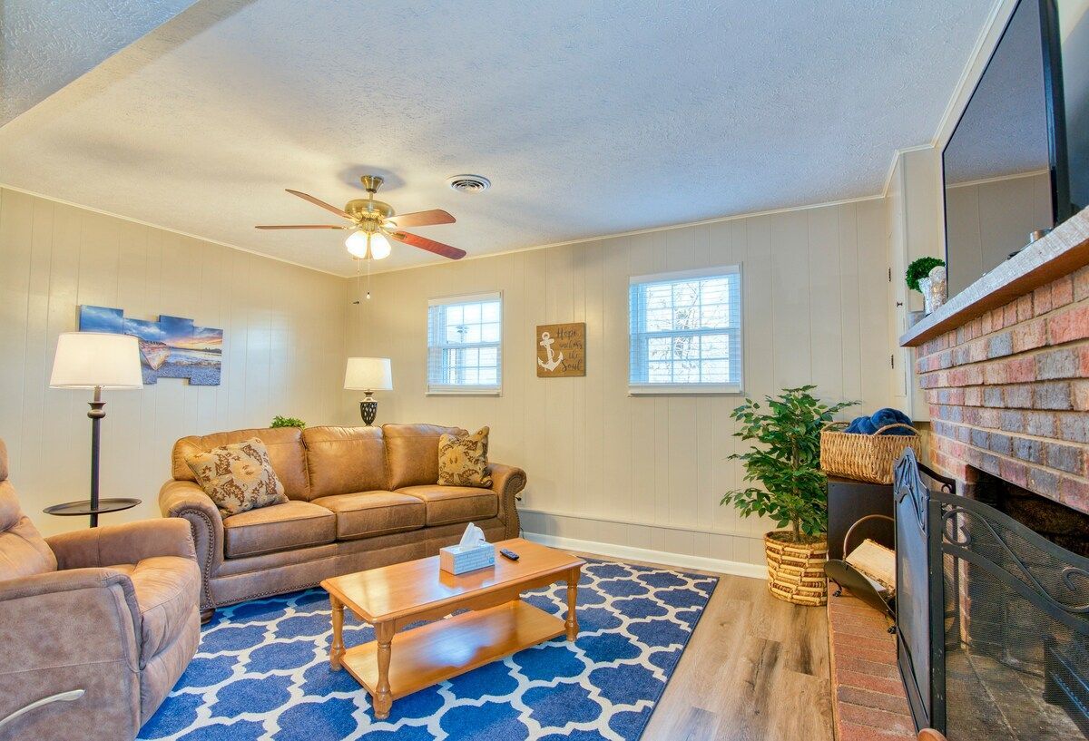 Gorgeous living room with brown leather couches, fireplace, and large TV in TN Livin's Johnson City Home