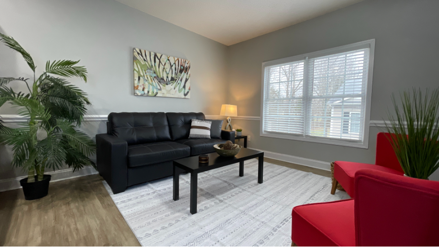 A living room with a couch , chair , table , lamp and television.
