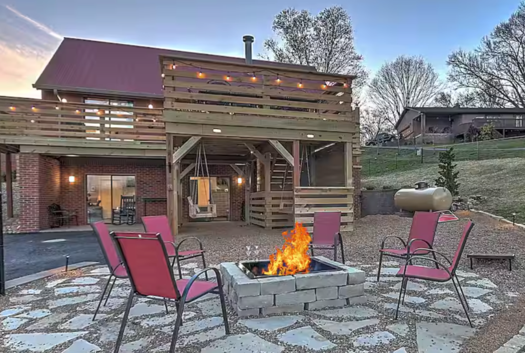 Book Now! Gorgeous living room with brown leather couches, fireplace, and large TV in TN Livin's Johnson City Home