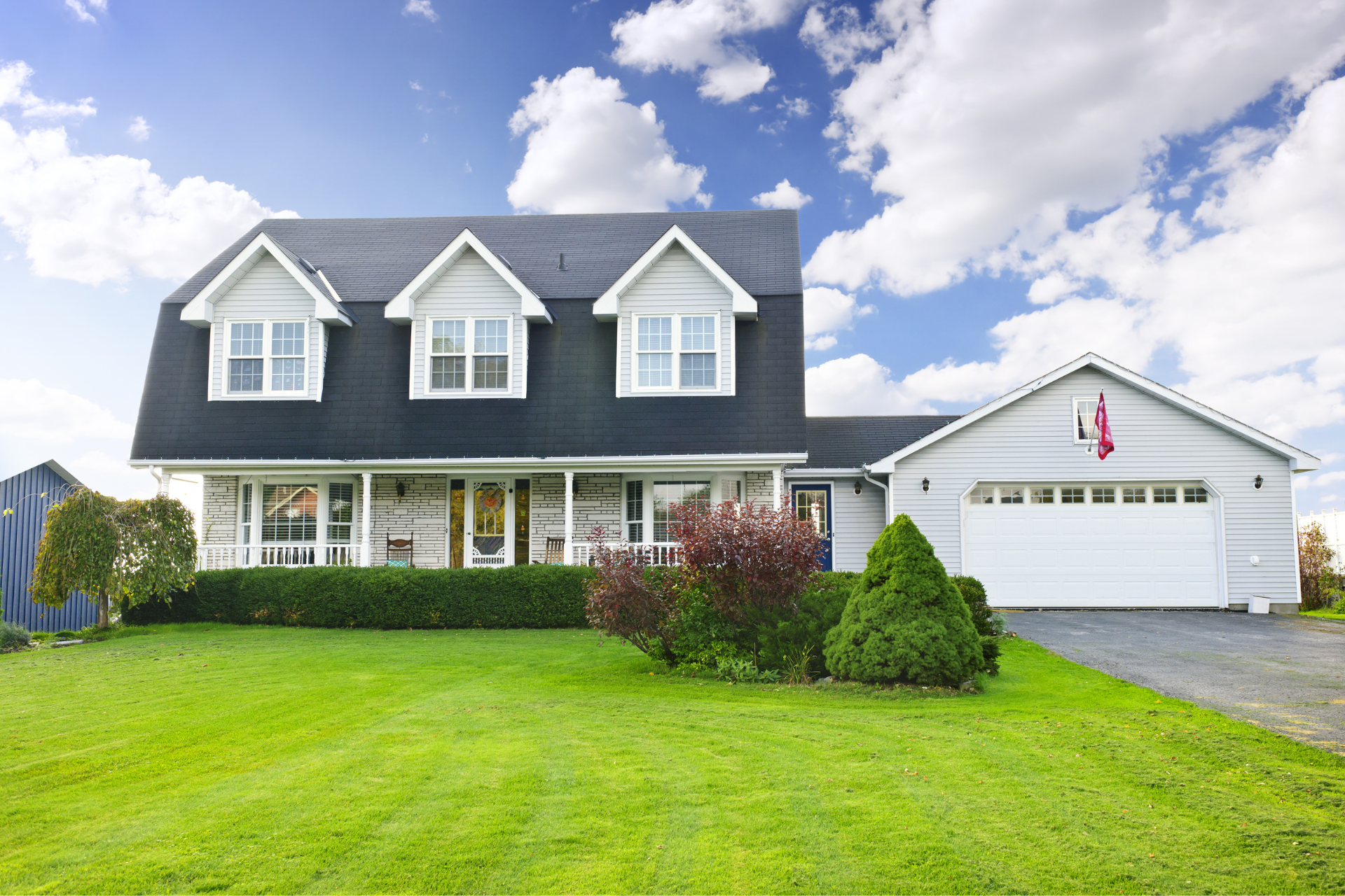 A large white house with a black roof and a white garage door