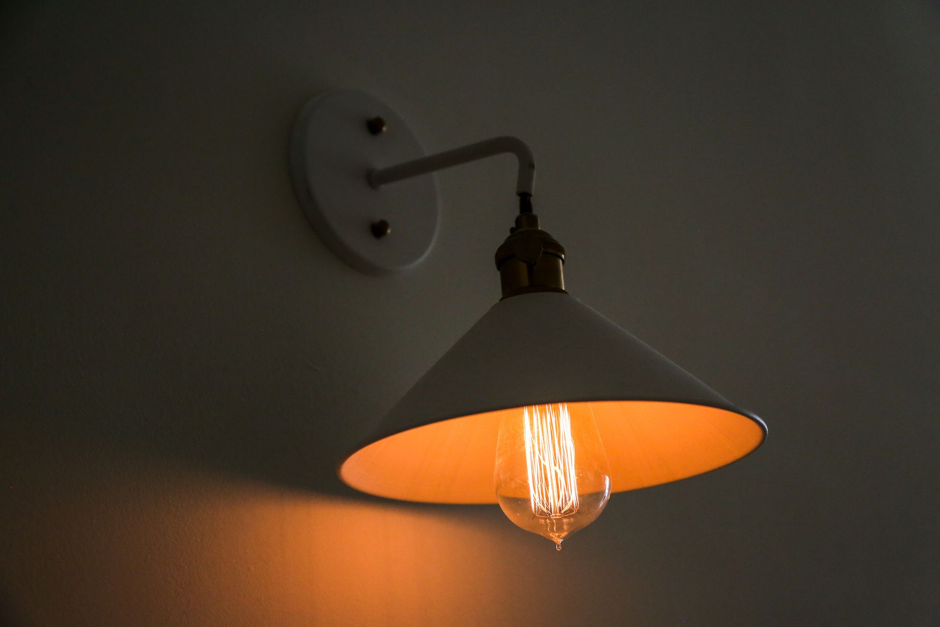 A light bulb is hanging on a wall with a white shade.