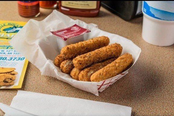 A basket of mozzarella sticks with ketchup on a table