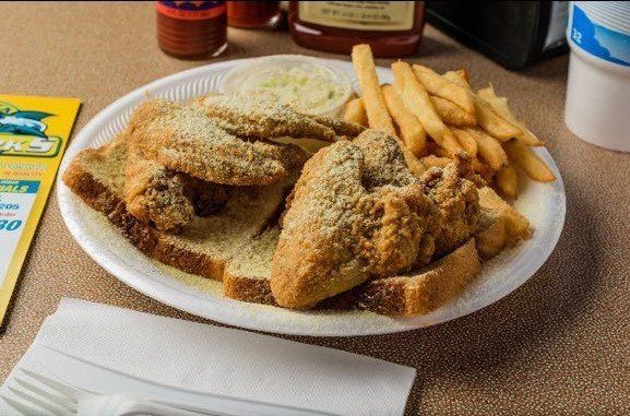A plate of fried fish and french fries on a table.