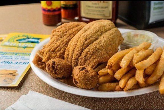 A plate of fried fish and french fries on a table.