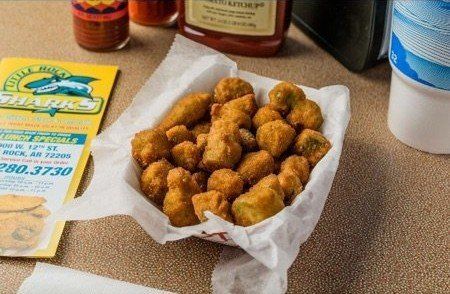 A basket of fried pickles sits on a table next to a menu.