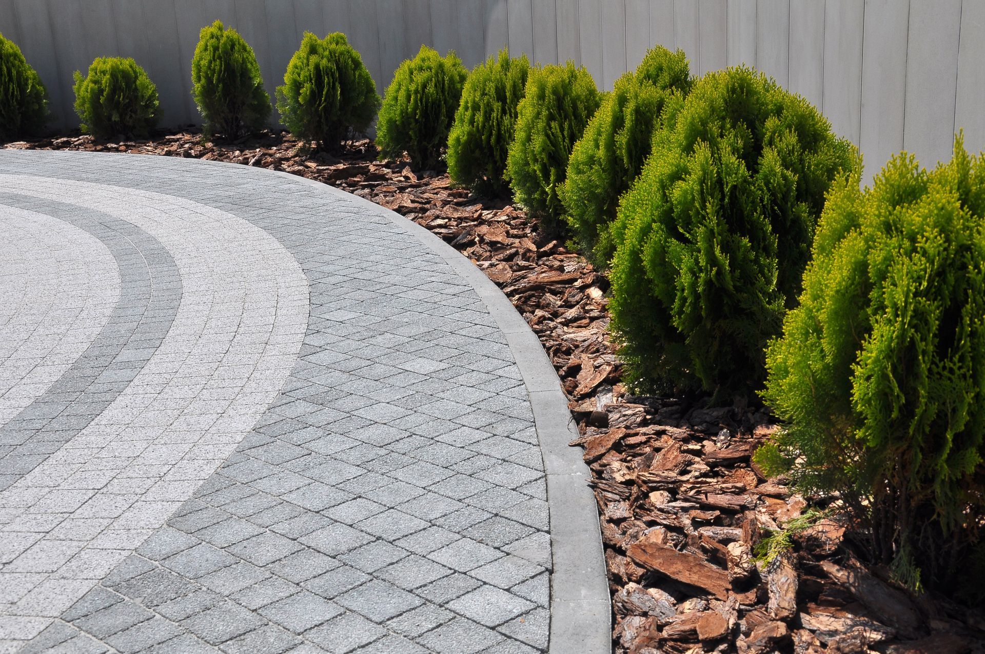A circular driveway surrounded by shrubs and mulch