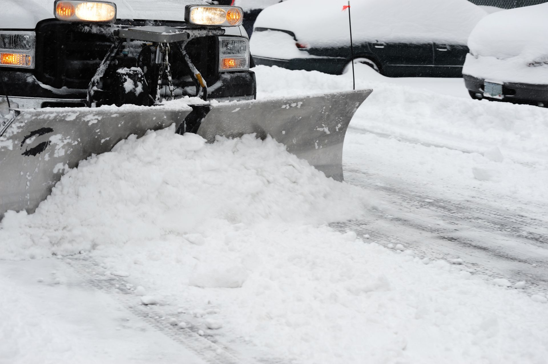 A snow plow is clearing snow from a parking lot