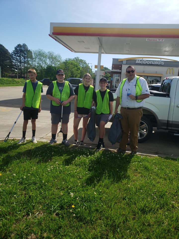 A group of people are standing in front of a gas station.