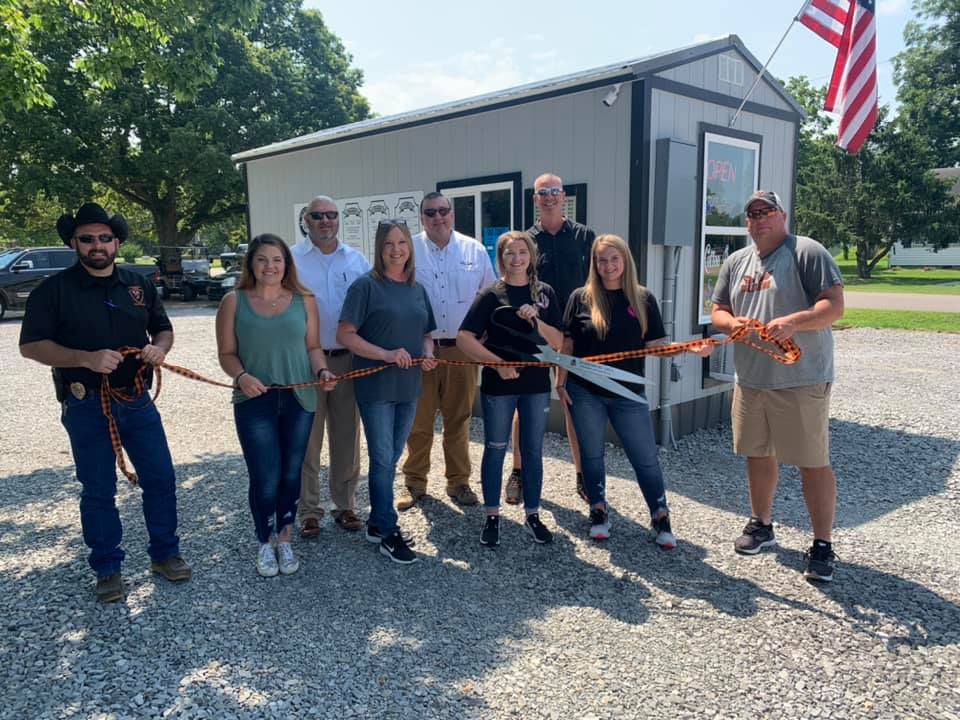 A group of people are standing in front of a building cutting a ribbon.