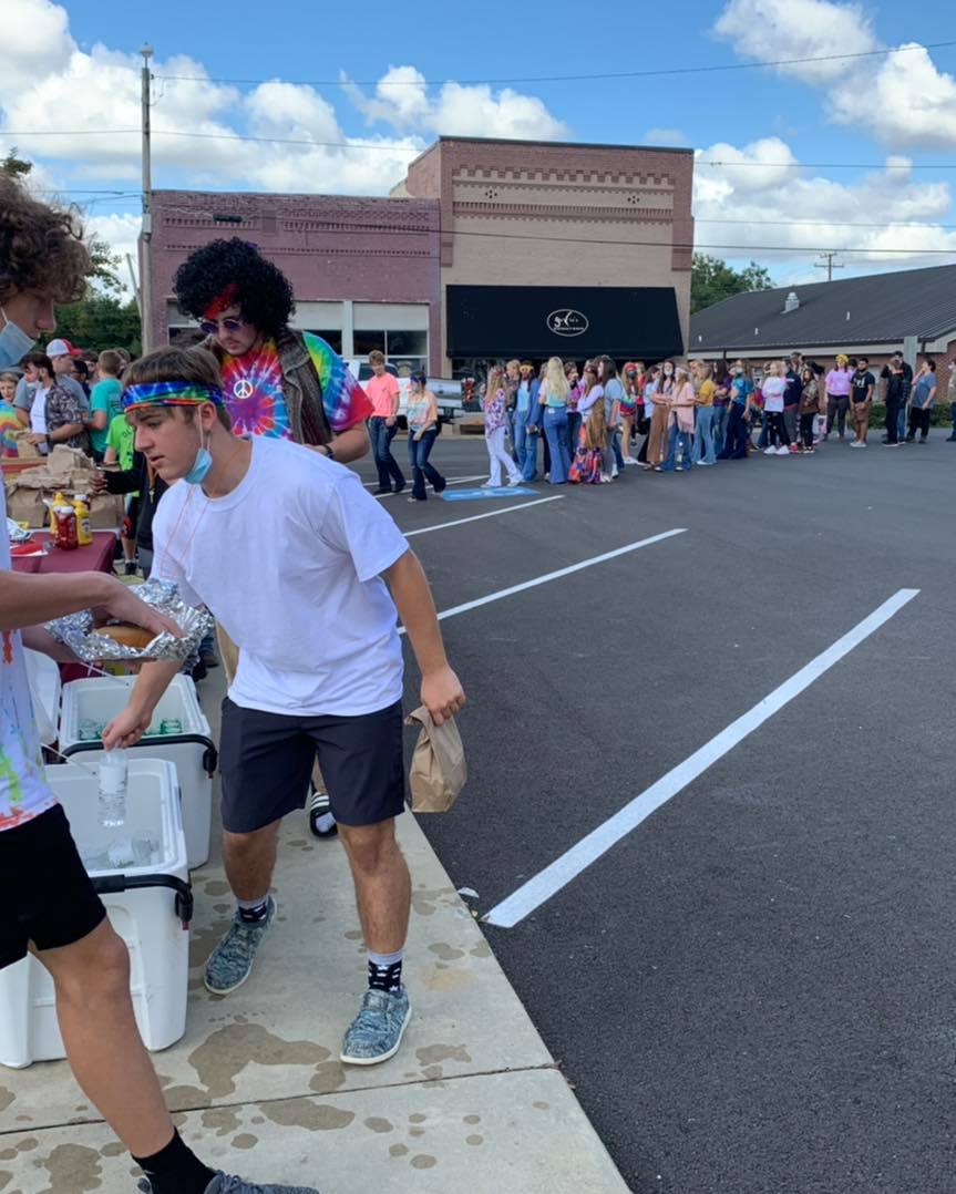 A group of people are standing on a sidewalk in front of a building.