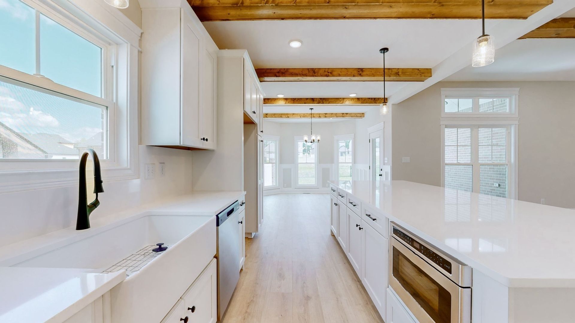 A kitchen with white cabinets , stainless steel appliances , a sink , and a large island.