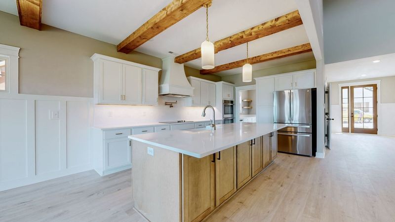 A kitchen with white cabinets , stainless steel appliances , and a large island.