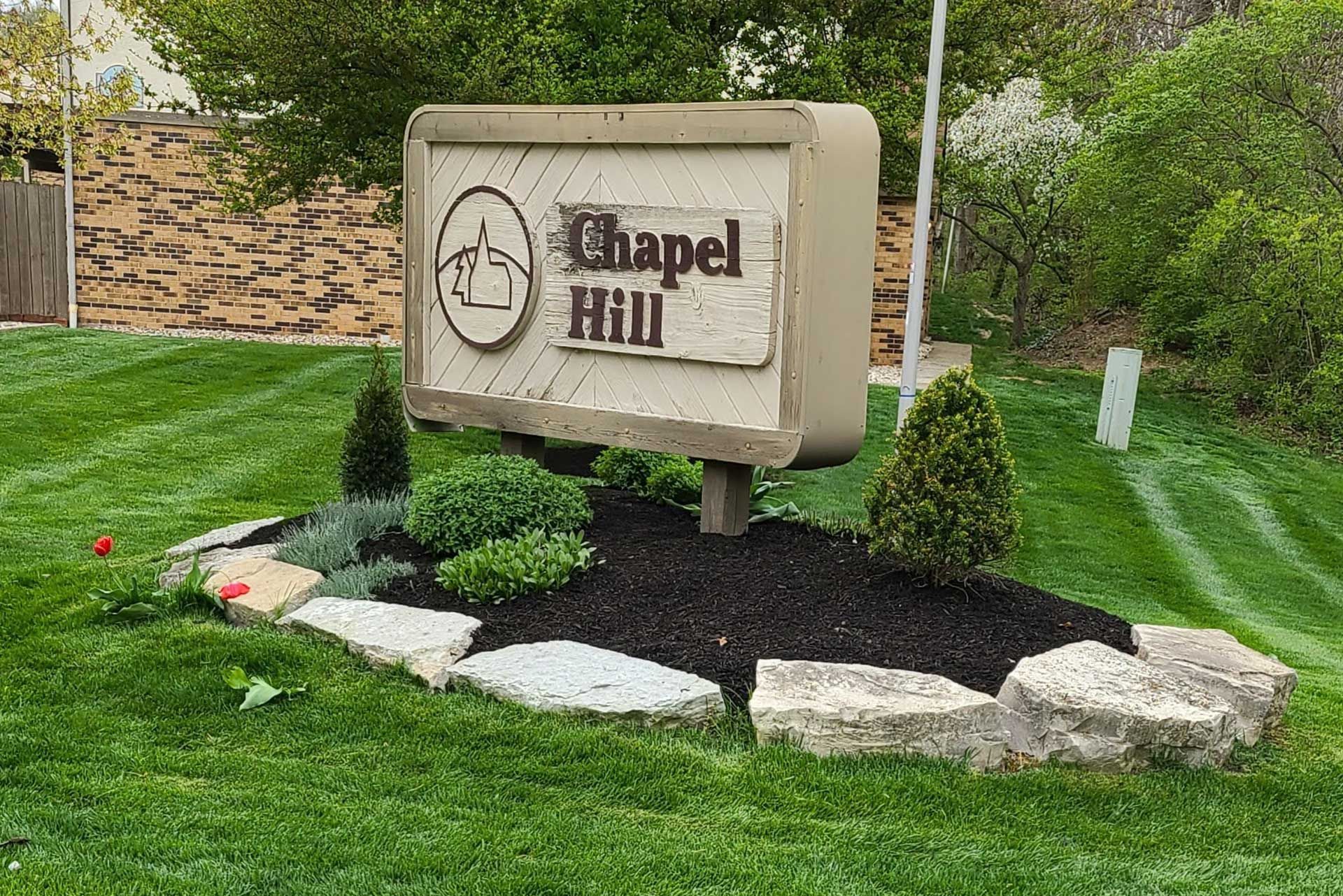 Chapel Hill sign with a horse logo surrounded by landscaping, on a grassy lawn.