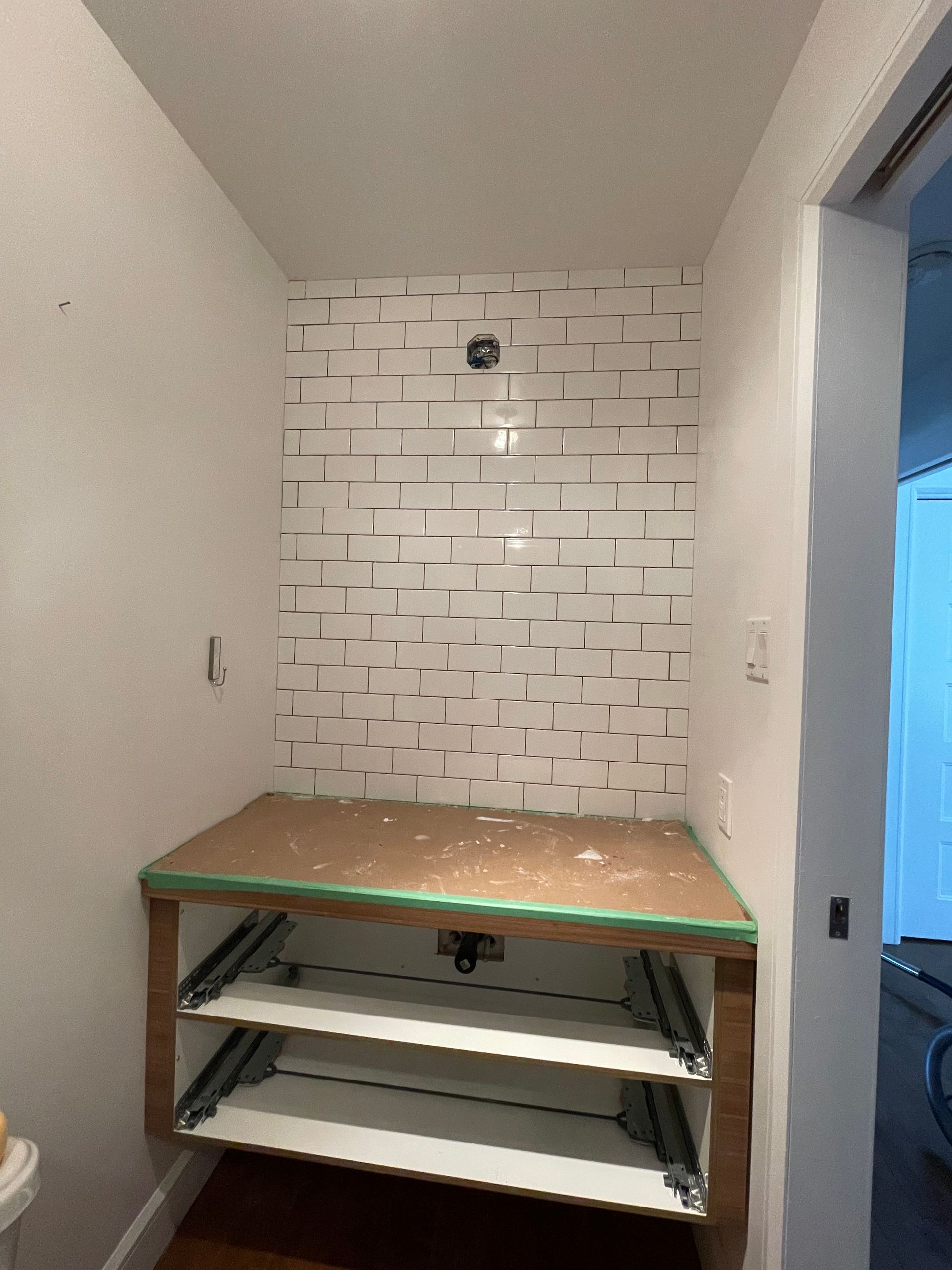 Un meuble bas intégré avec une crédence en carrelage métro blanc installée au-dessus.