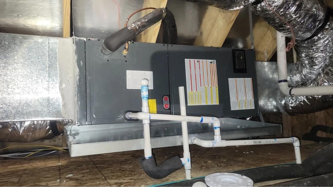 An air conditioner is sitting under a ceiling in a basement.