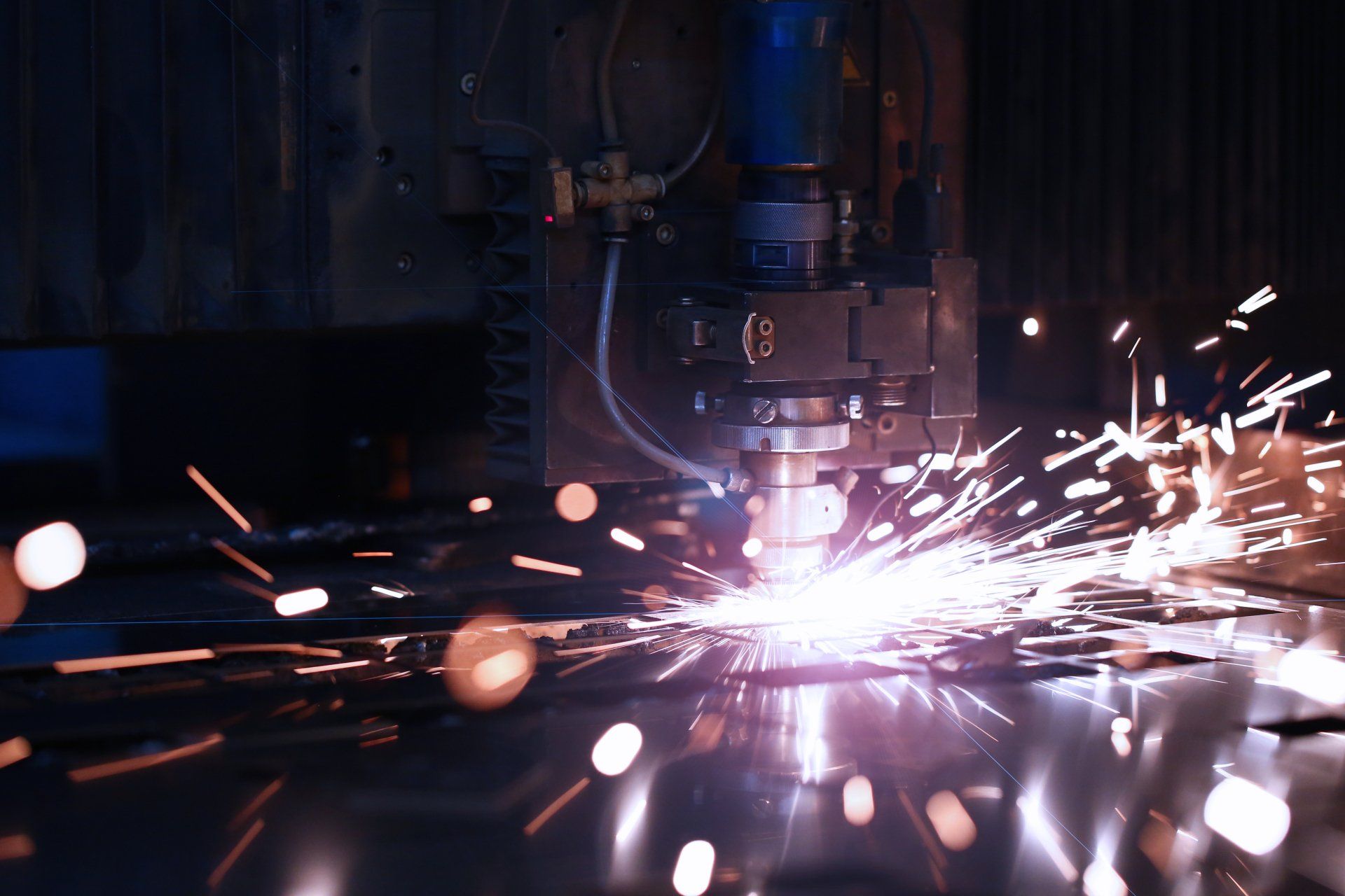 Une machine coupe un morceau de métal et des étincelles en sortent.