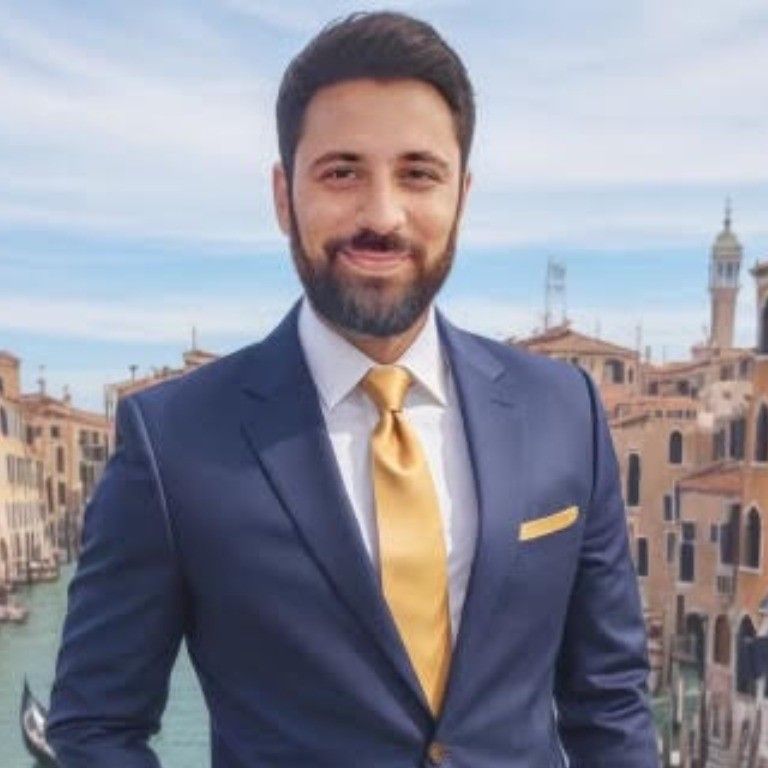 A man with a beard wearing a blue suit and yellow tie