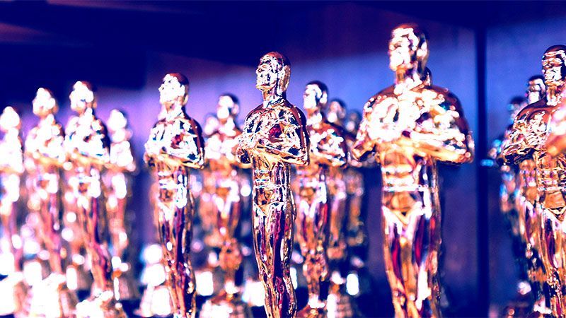 Shelf stacked with gold awards that look like Oscars