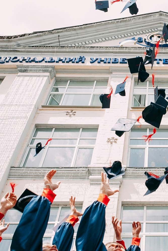 Graduates throwing their hats in the air outside a university building