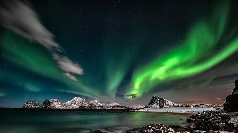 Mountainous landscape at night with the northern lights dominating the sky