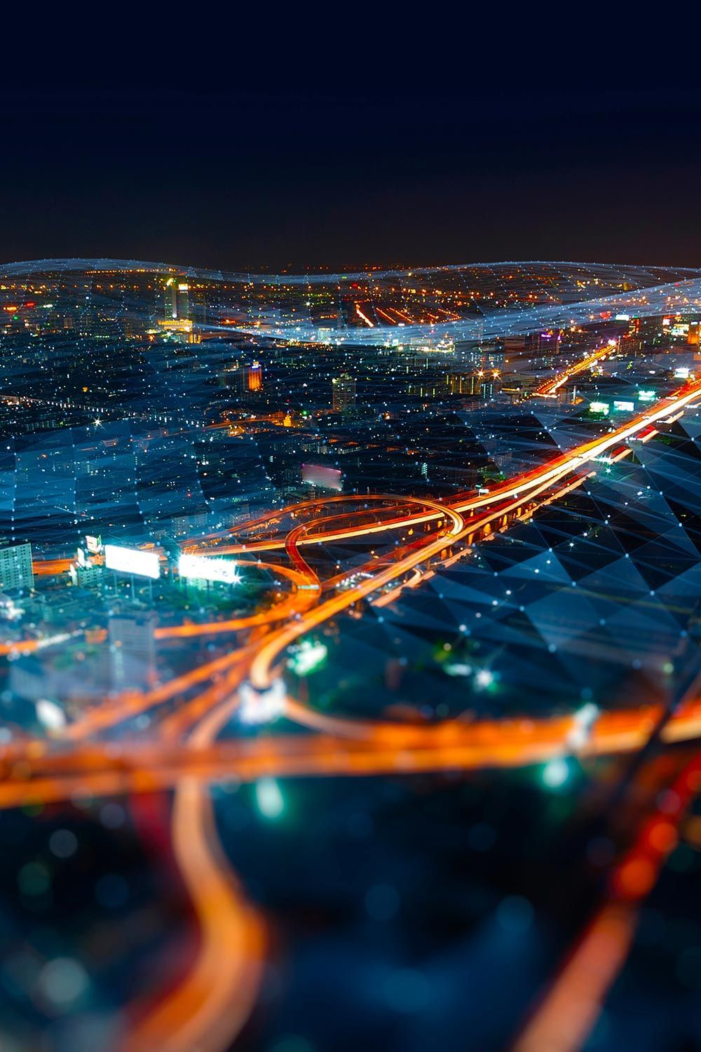 Aerial night view of city with overlay of a vast interconnected network and highways of information in orange