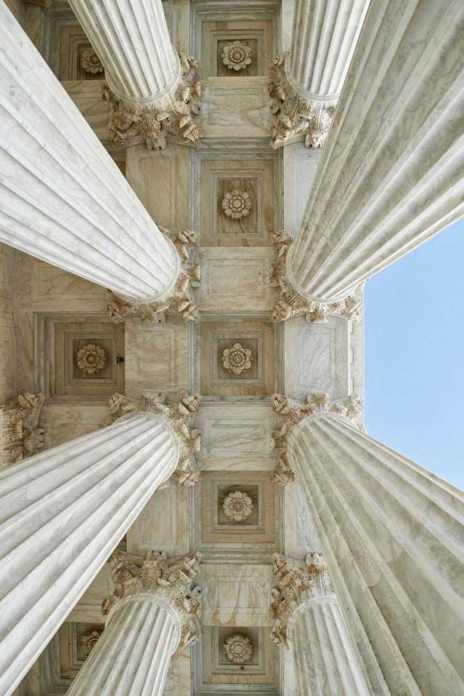 Ground up shot of white pillars ascending to the roof of a public building