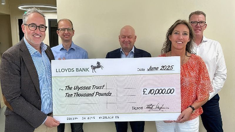 Cambridge MC Falklands team standing with Polly Marsh, CEO of the Ulysses Trust, holding a cheque